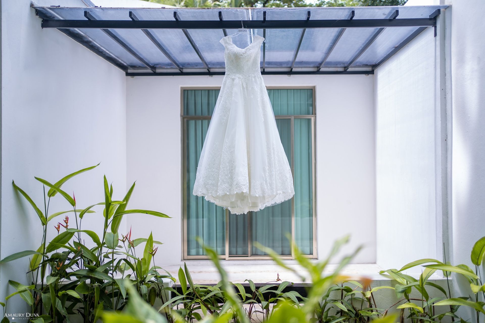 Un vestido de novia blanco cuelga en una percha delante de una ventana.