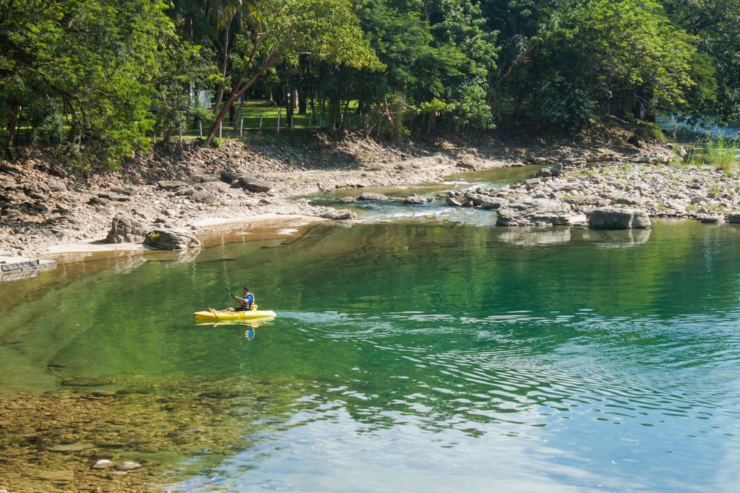 Una persona está montando un kayak amarillo en un río.