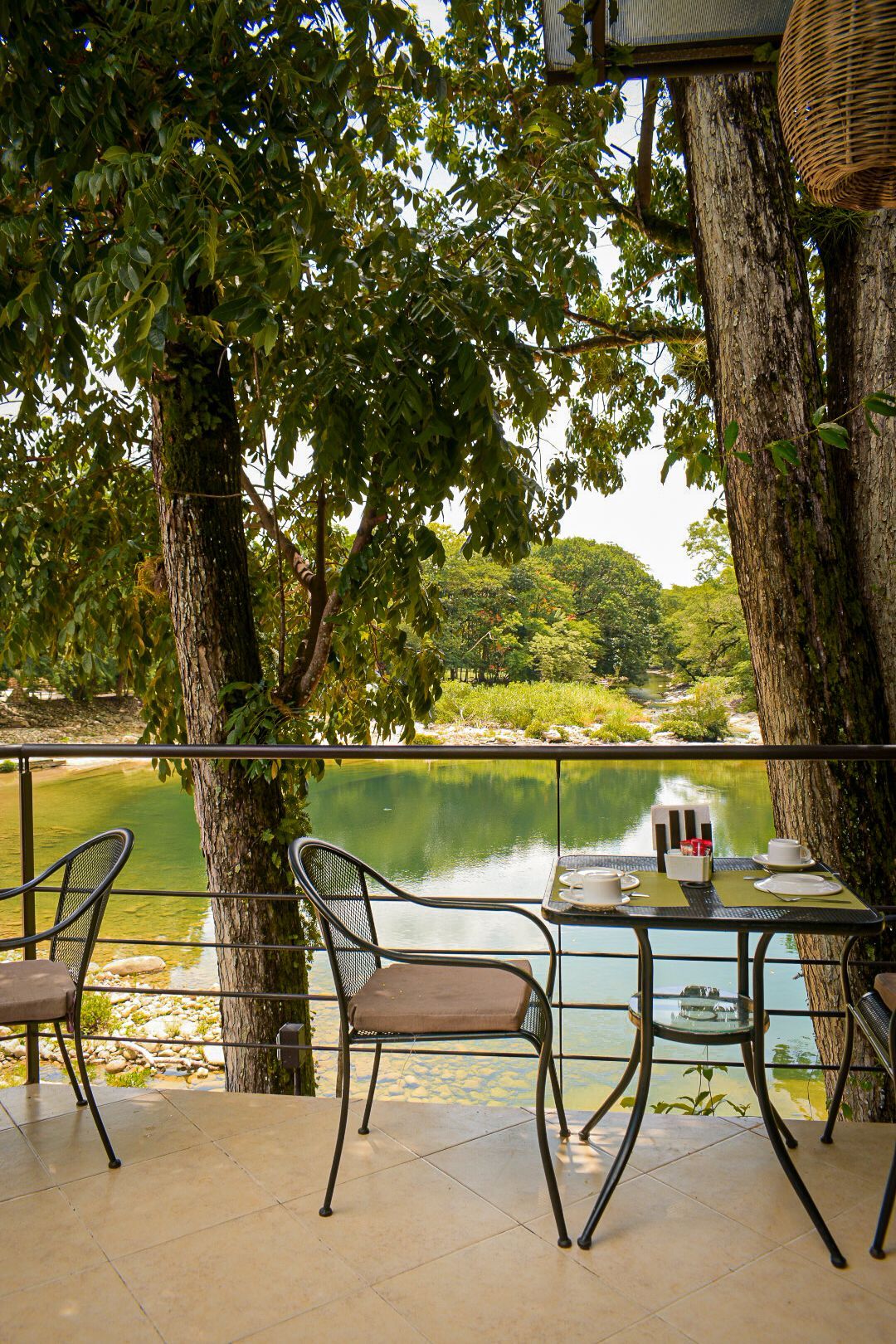 Una mesa y sillas en un balcón con vista a un lago.