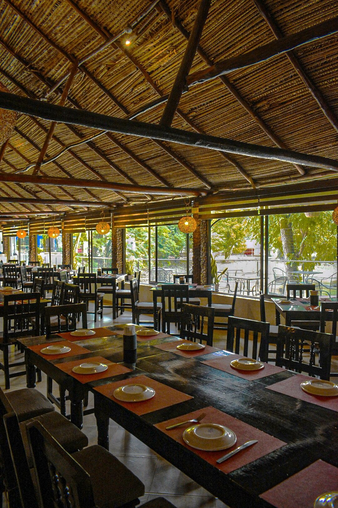 Un restaurante con mesas y sillas y techo de paja.