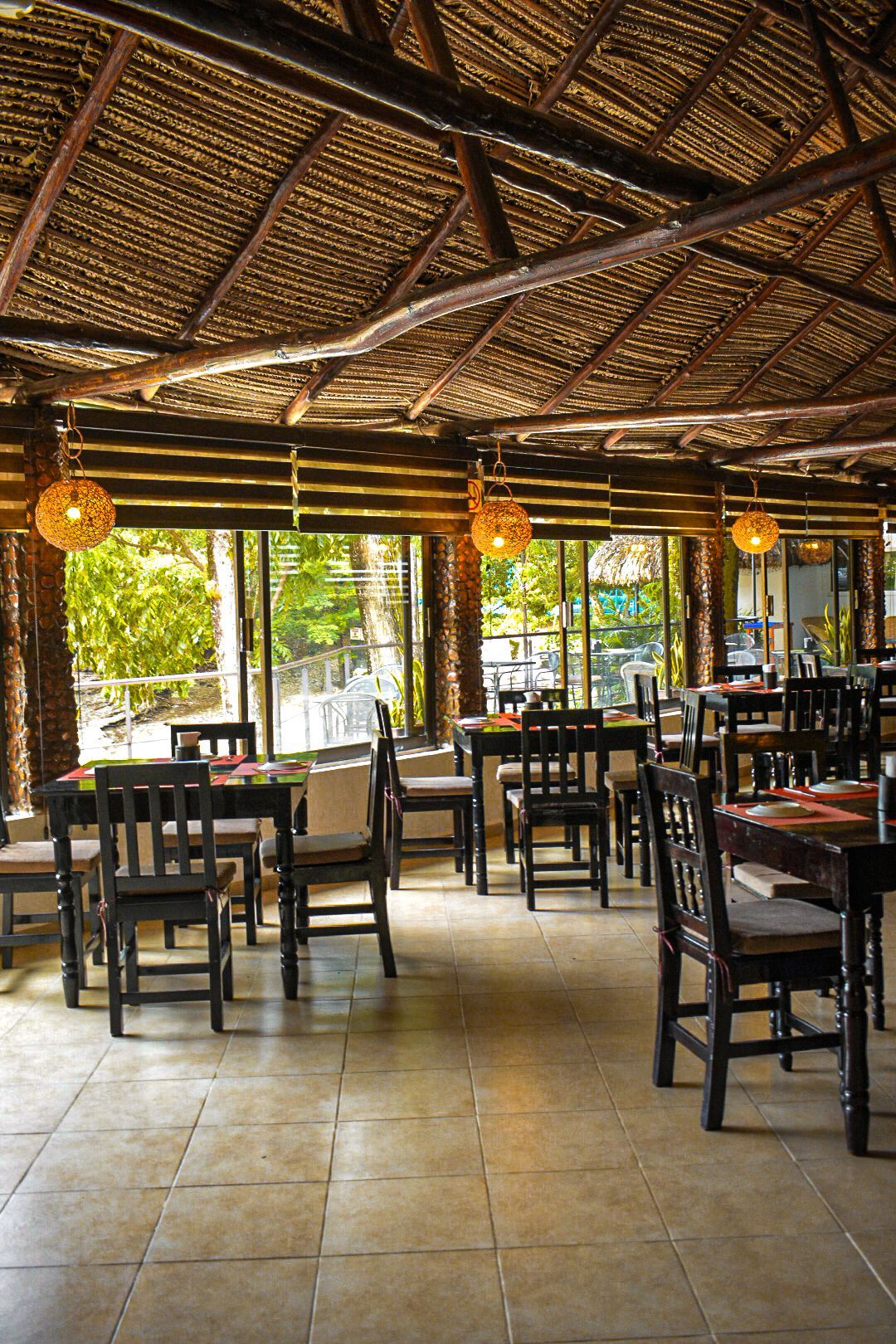 Un restaurante con mesas y sillas y techo de paja.