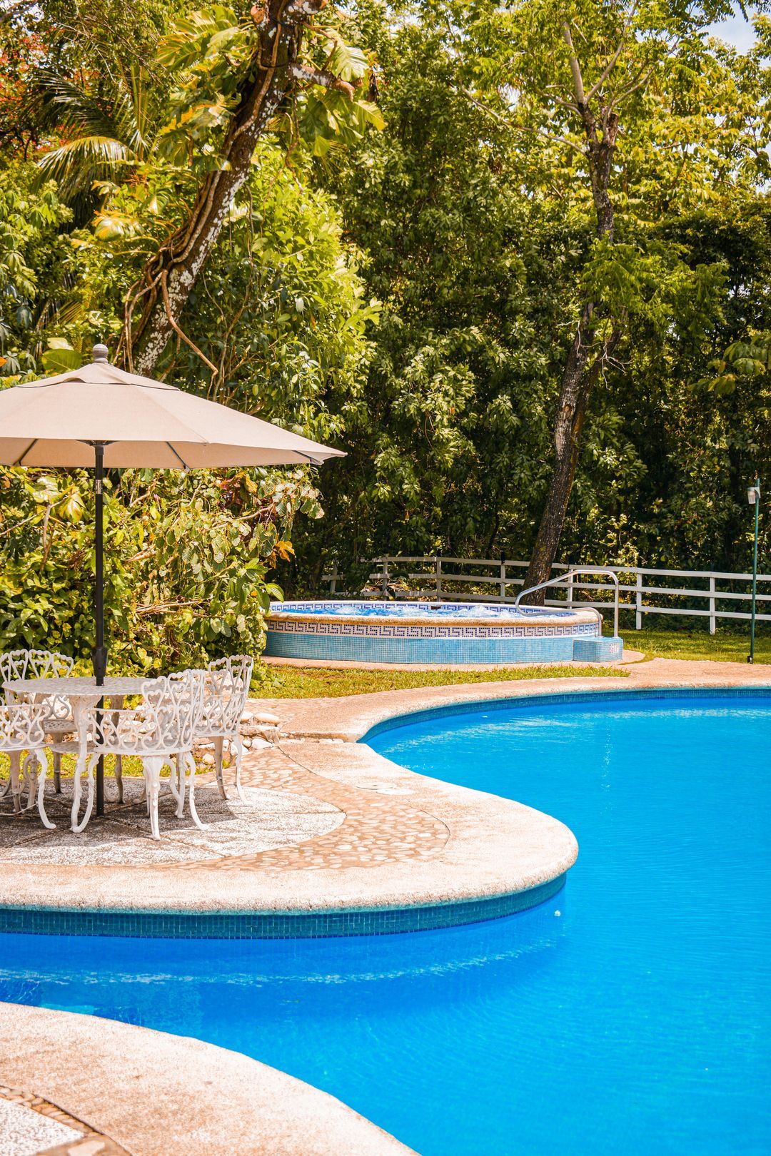 Una gran piscina con mesa, sillas y sombrilla.