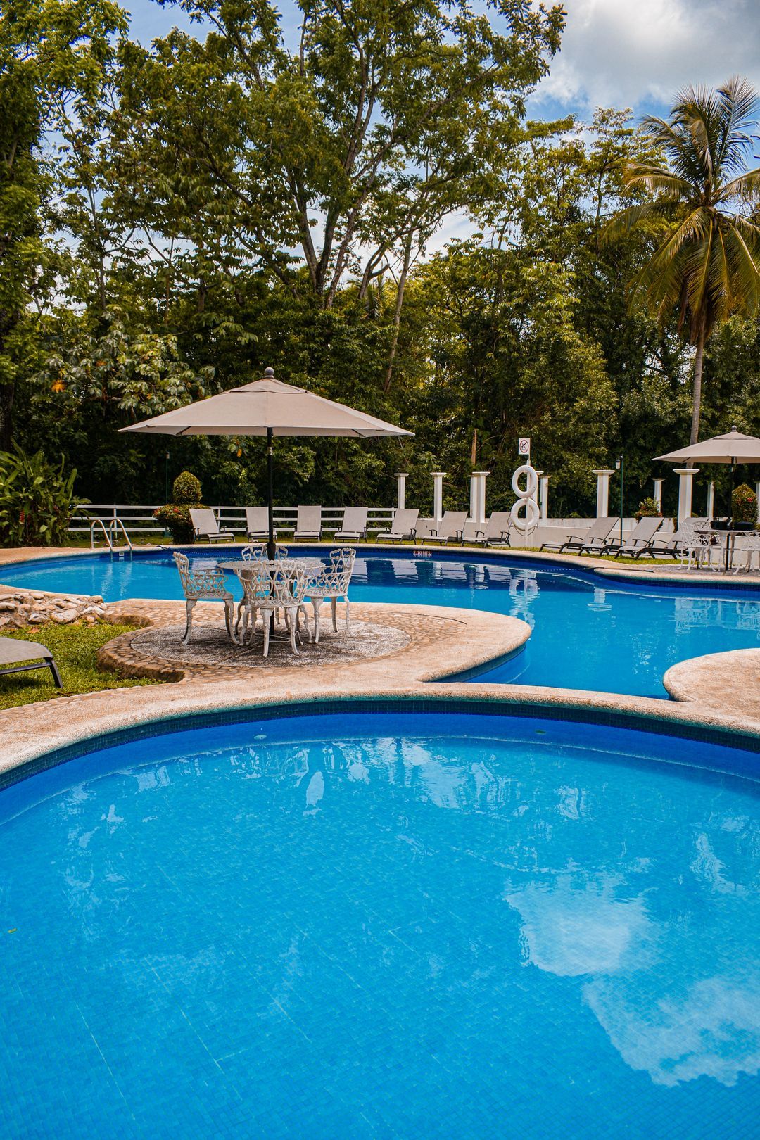 Una gran piscina con sombrillas y sillas a su alrededor.