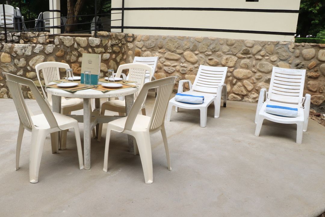 Una mesa y sillas en un patio frente a un muro de piedra.