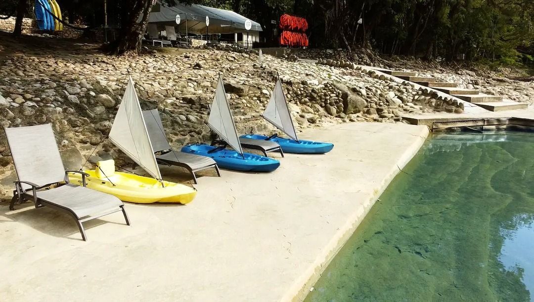Una fila de sillas y kayaks están sentados al lado de una piscina.