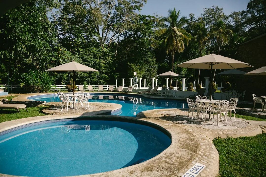 Una gran piscina con sombrillas y sillas alrededor.