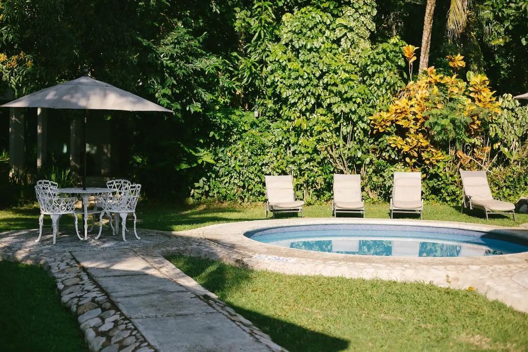 Una piscina con una mesa y sillas y una sombrilla en el patio trasero.