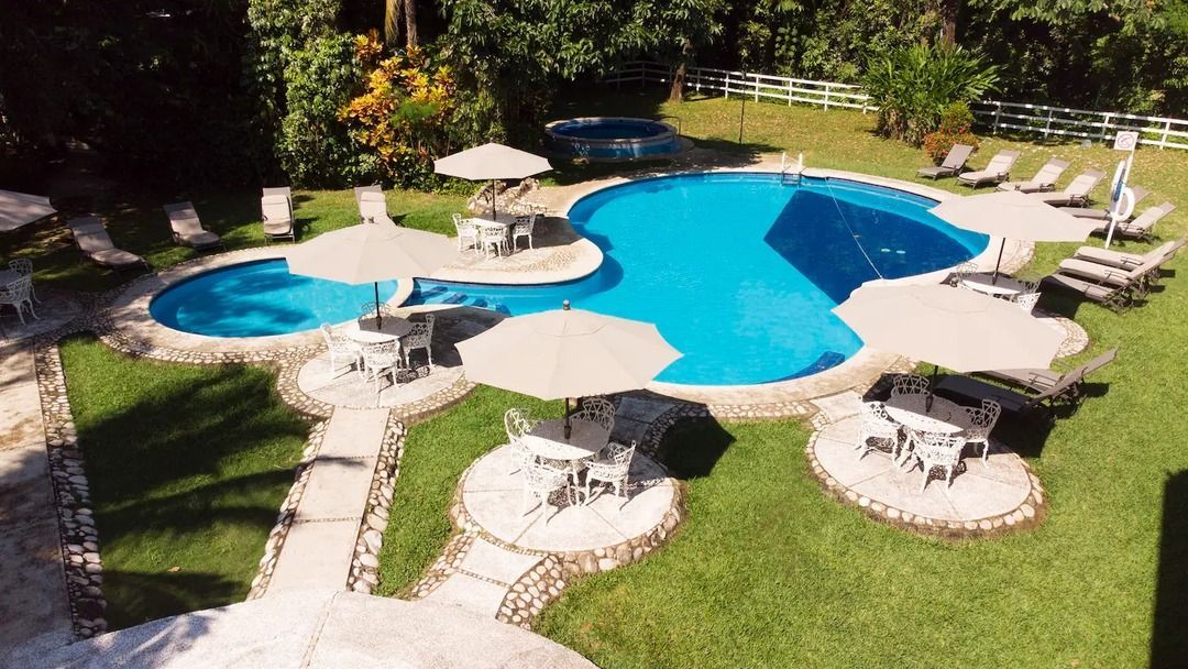 Una vista aérea de una gran piscina rodeada de sillas y sombrillas.
