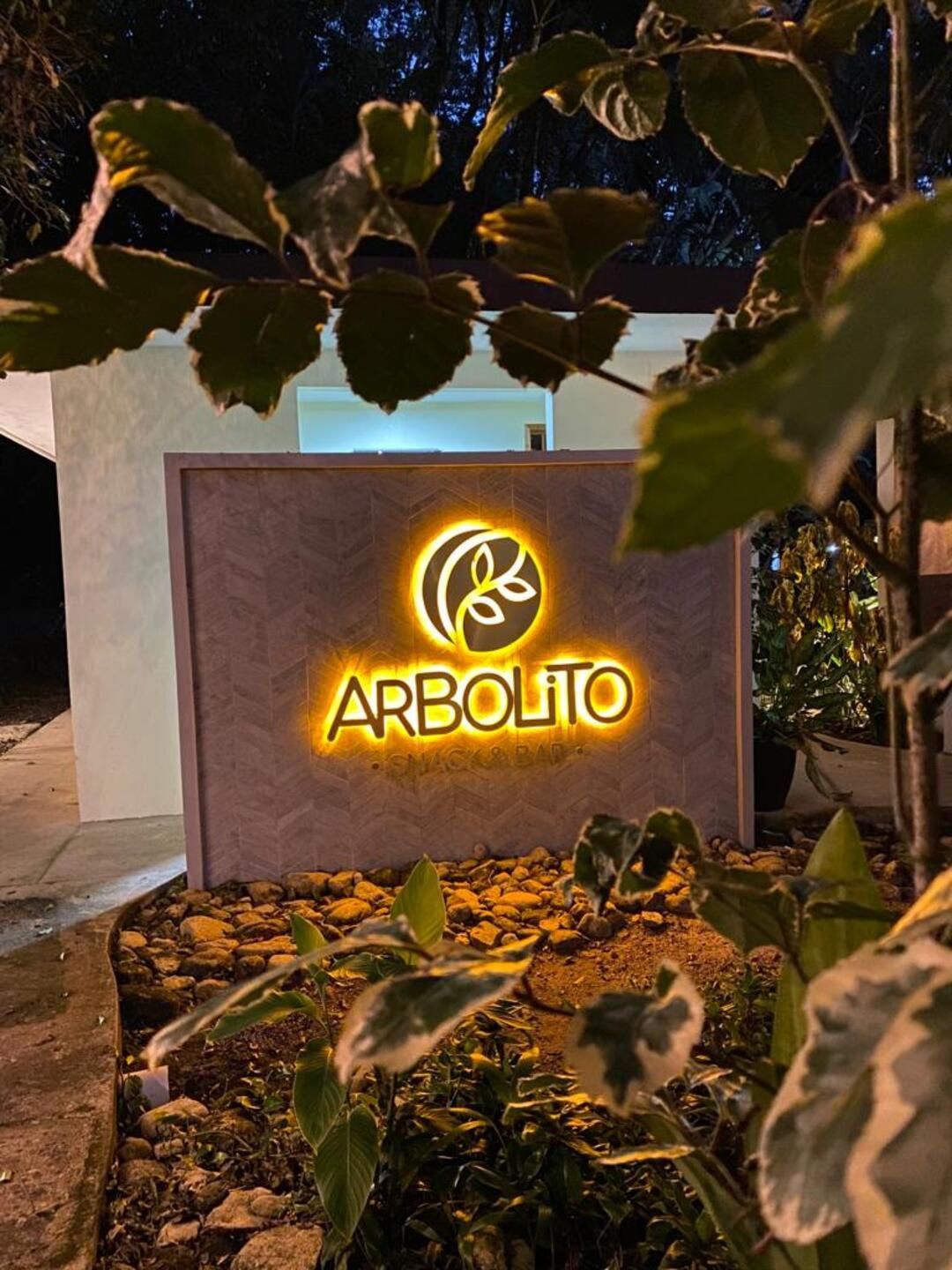Un cartel que dice arbolito está iluminado por la noche.