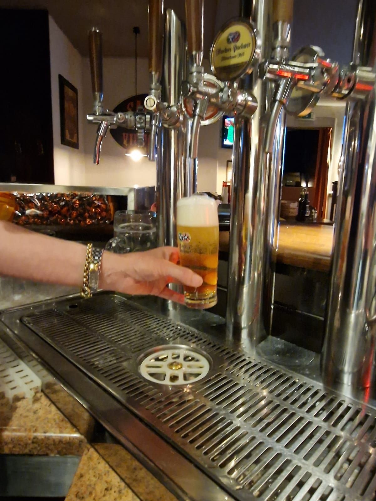 Persona che versa la birra dalla spina in un bicchiere in un bar.