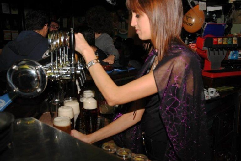 Barista che versa la birra alla spina, ambiente da bar buio.