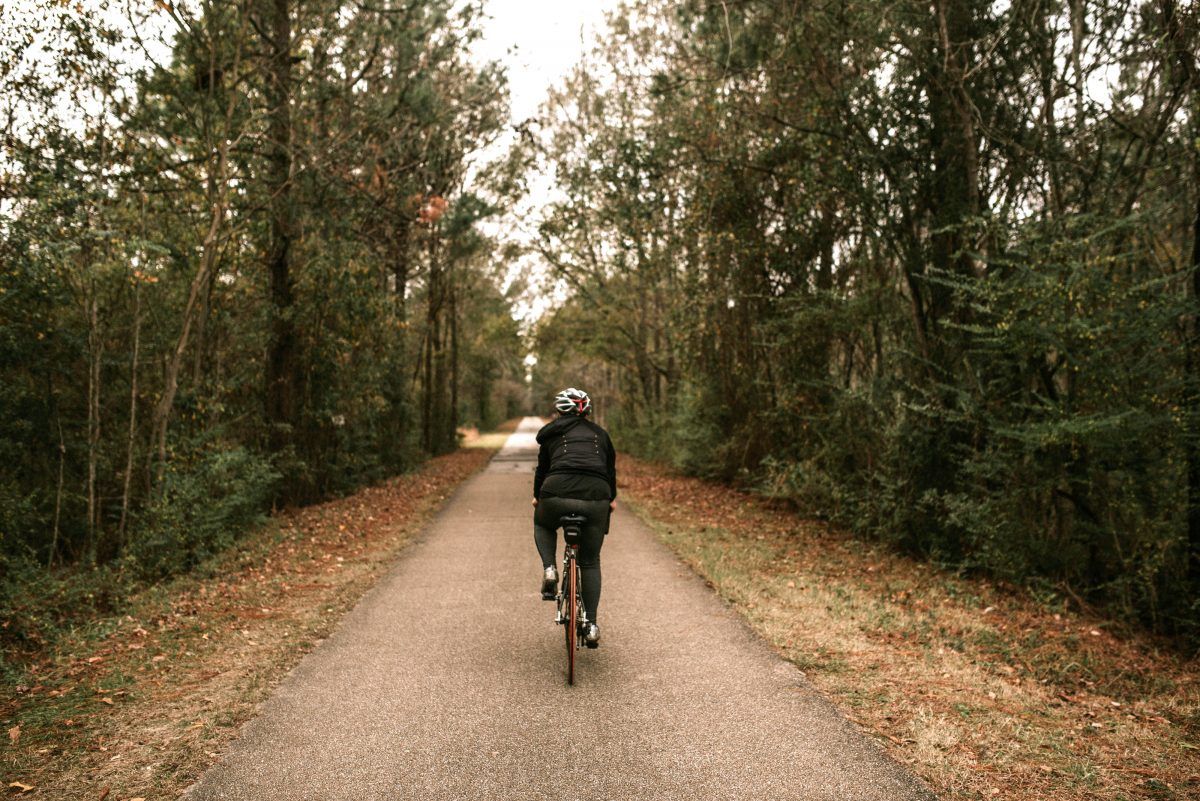 A person is riding a bike down a path in the woods.