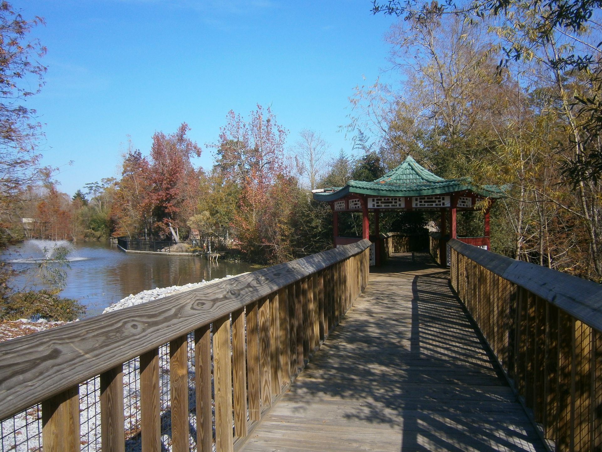A wooden bridge leading to a gazebo overlooking a lake