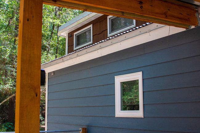 A blue house with a brown roof and a white window.