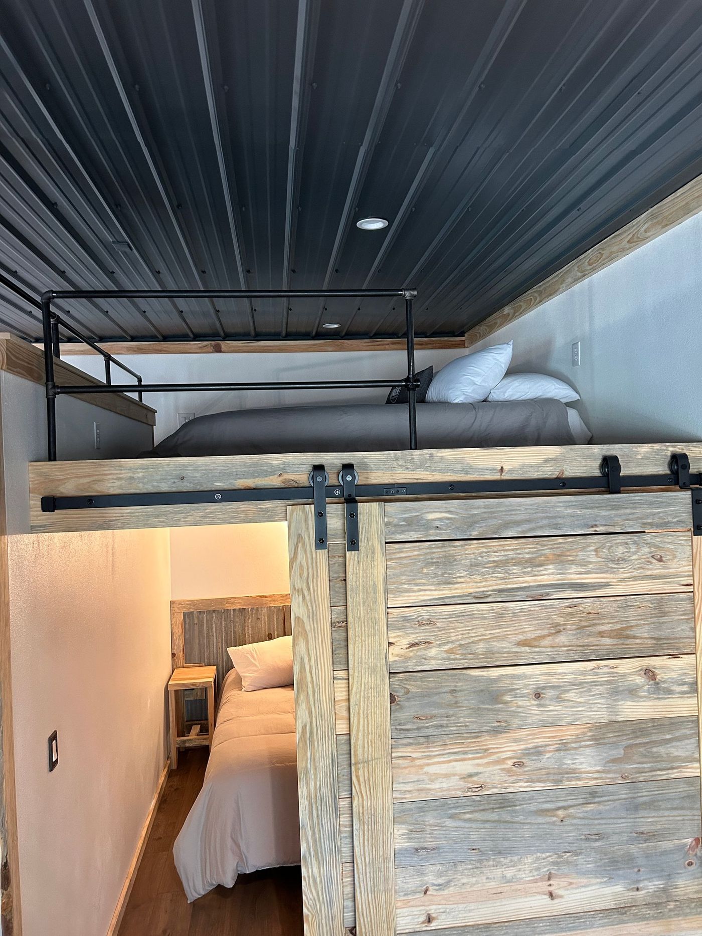 A bedroom with a bunk bed and a sliding barn door.