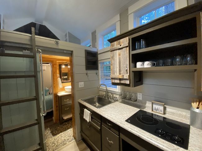 A kitchen in a small house with a sink , stove , and ladder.