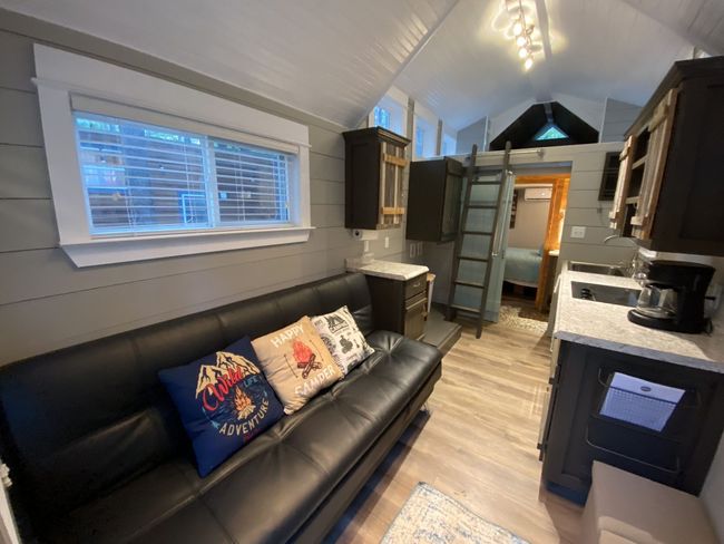 A living room with a couch and a kitchen in a small house.