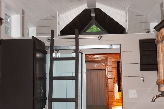 A ladder is leading up to a loft in a small house.