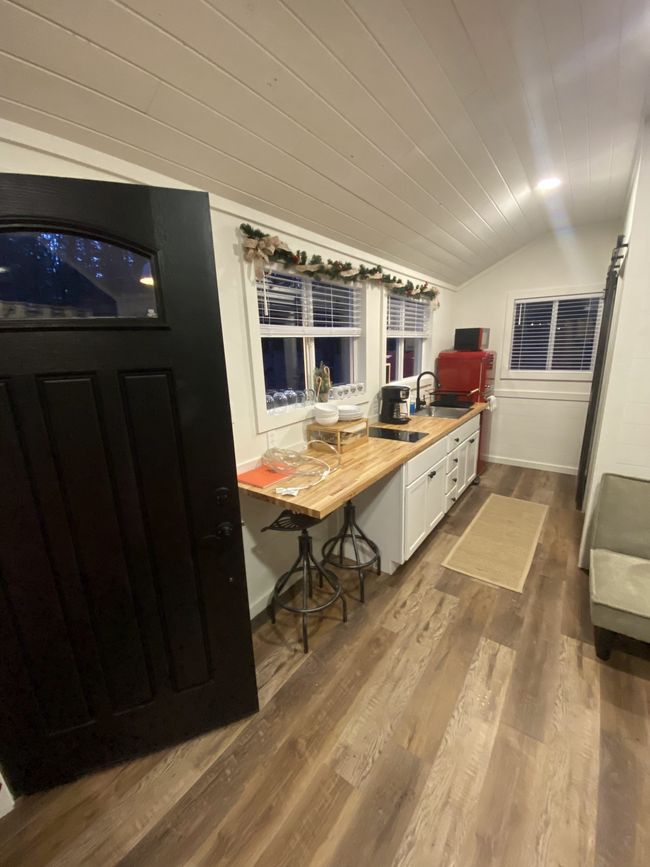 A kitchen with a black door and a wooden counter top.