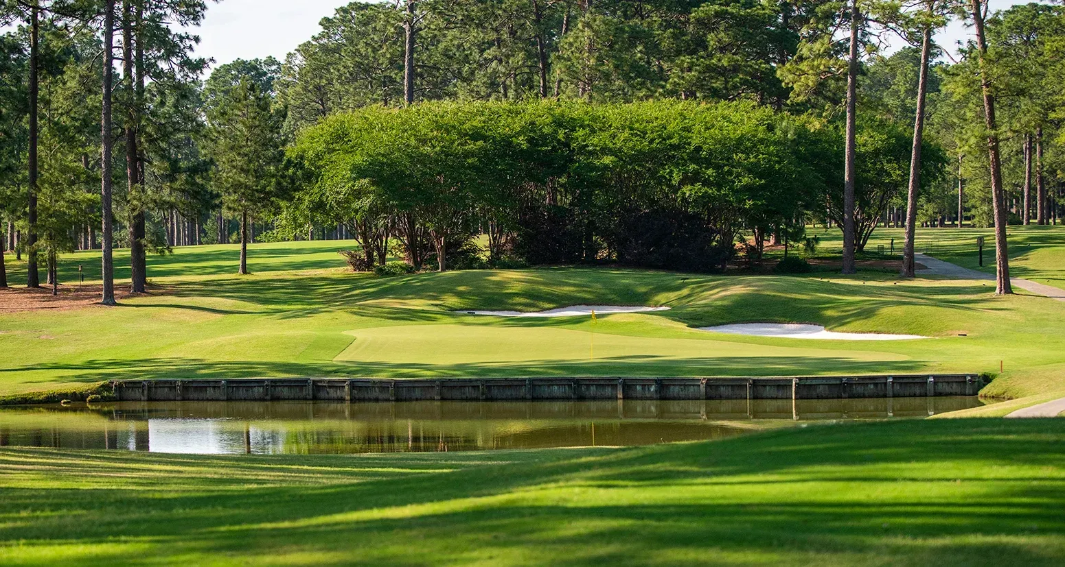 A golf course with trees and a sunset in the background