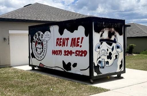 A large dumpster with a cow-themed design that reads 