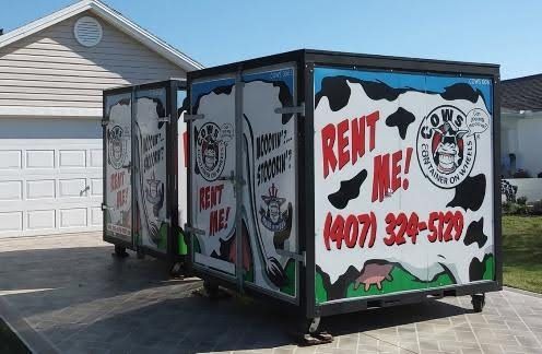 Two mobile storage containers with cow-themed advertising, offering rentals; number (407) 329-5729.
