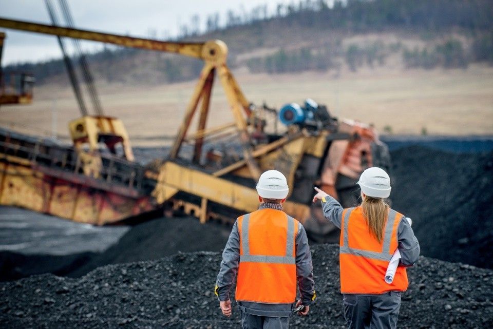 A man and a woman are walking in a coal mine.