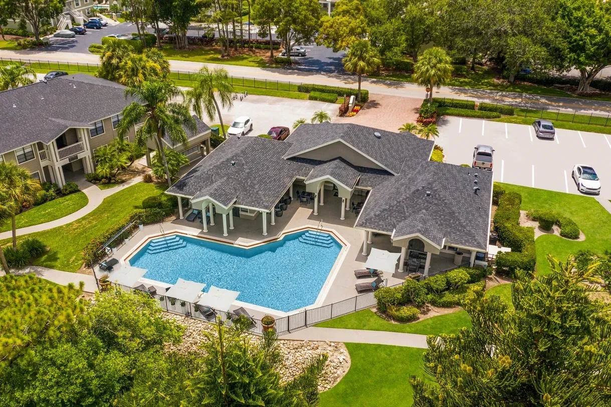 An aerial view of a swimming pool in a residential area surrounded by trees at Belvedere at Quail Run in Naples, FL.