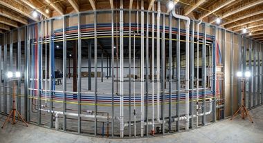 Curved metal wall framing with vertical studs and braces in an unfinished construction site