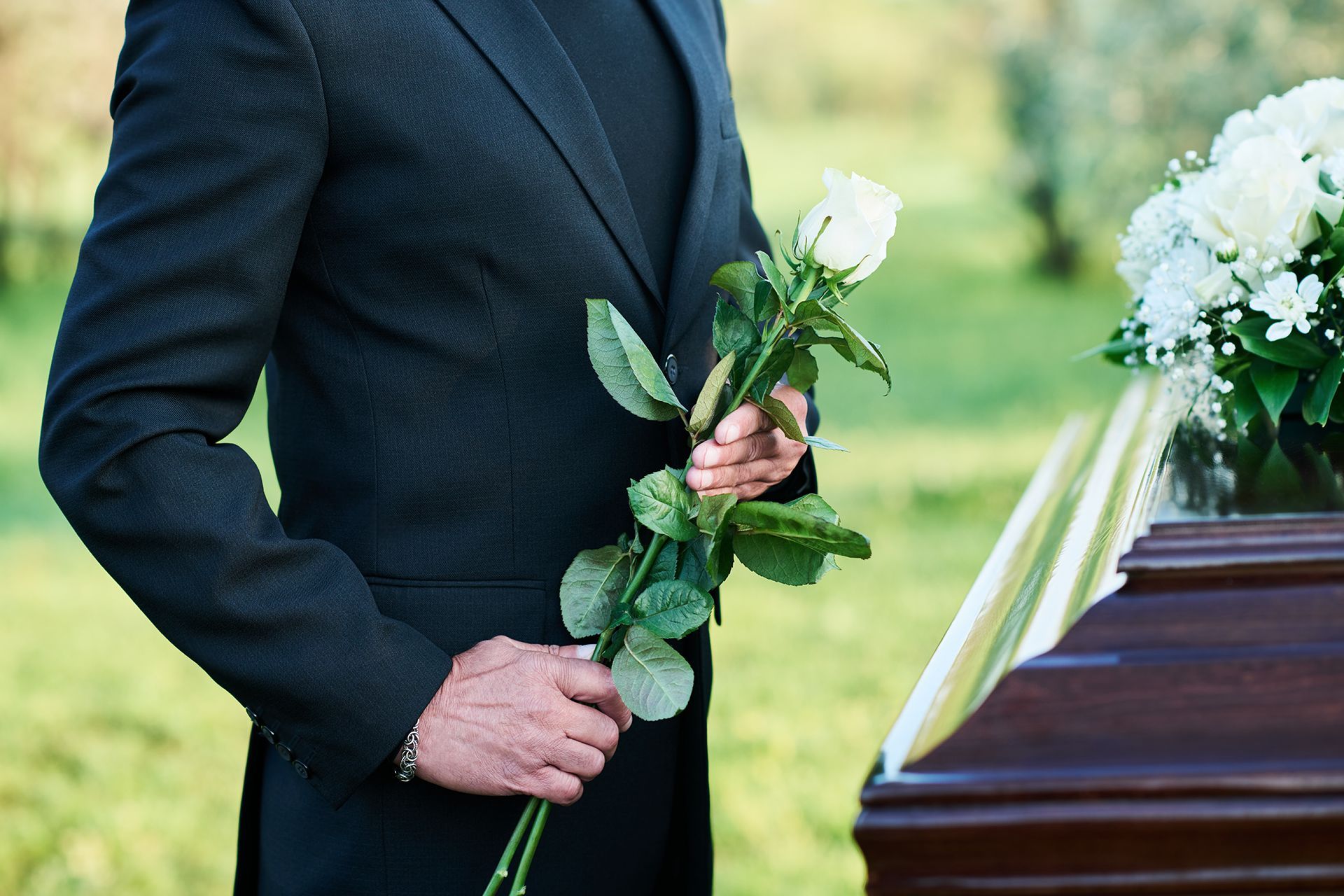 A blue coffin with pink roses on top of it in a cemetery.