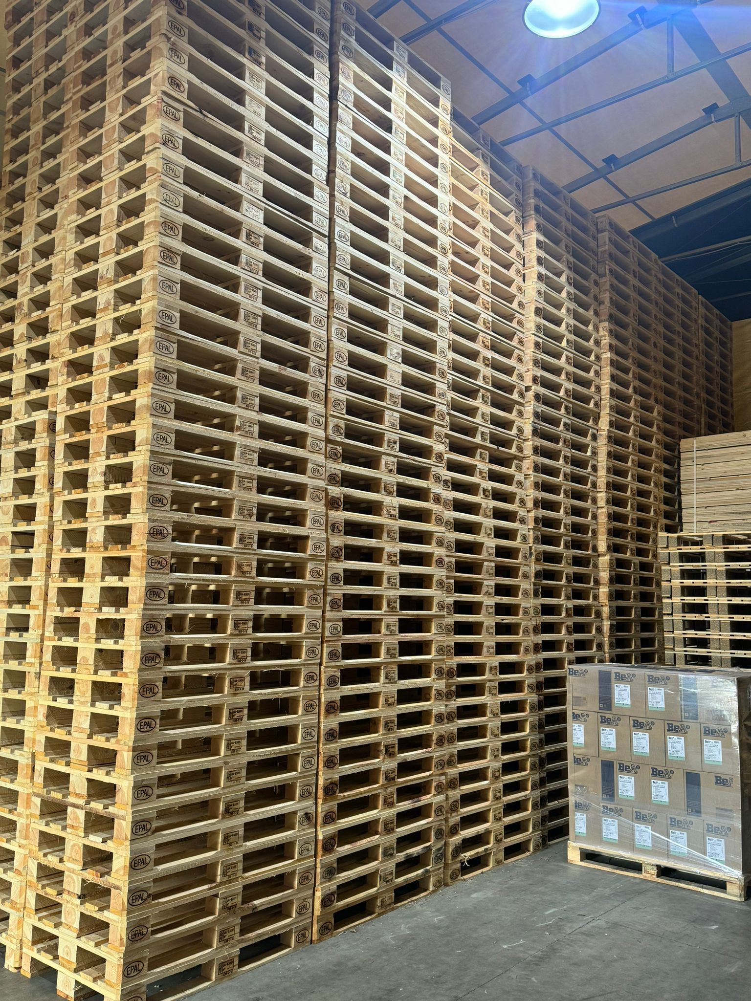 Pallet di legno impilati in alto all'interno di un magazzino.