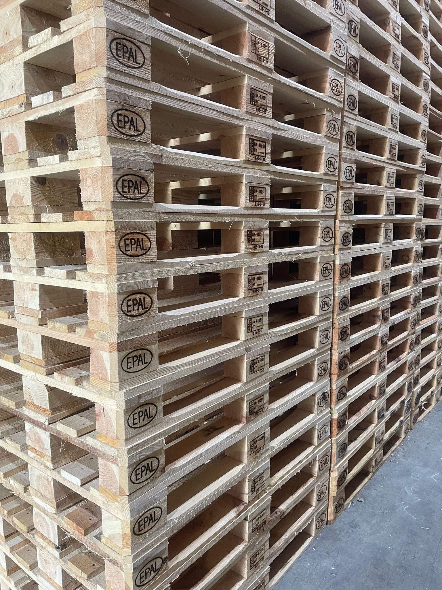 Pila di pallet in legno Europallet, marrone chiaro, con marcature e dettagli strutturali visibili.