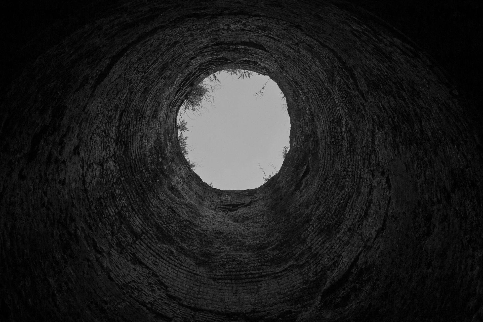 Dark circular tunnel or cave opening with bright white light at the center