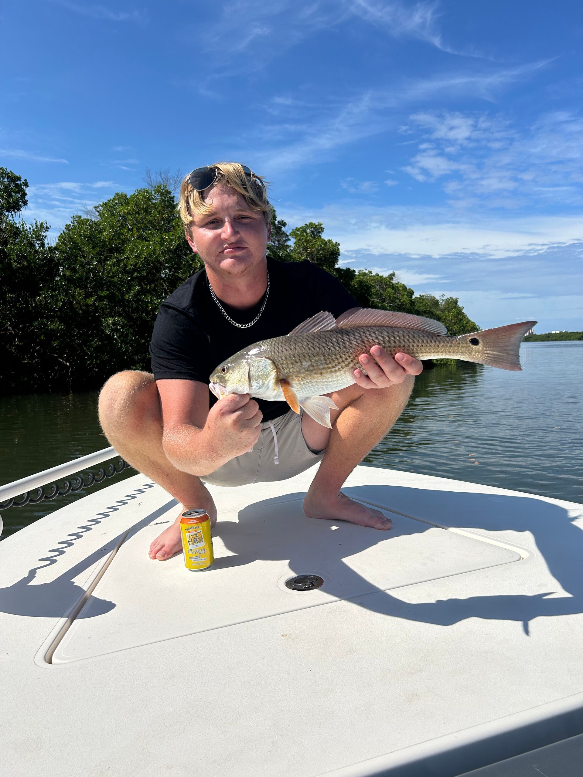 A man is kneeling on a boat holding a large fish.