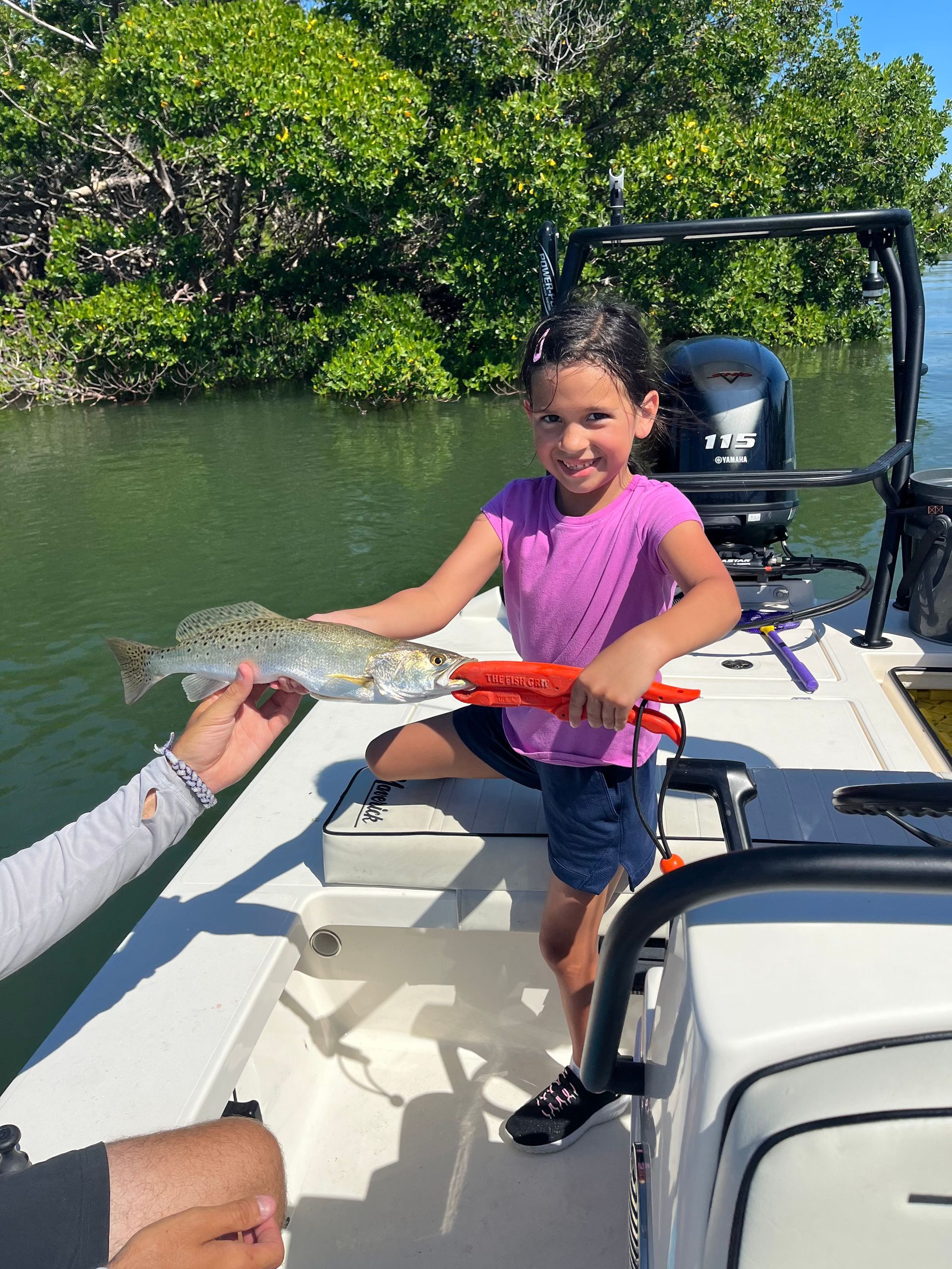 A little girl is sitting on a boat holding a fish.
