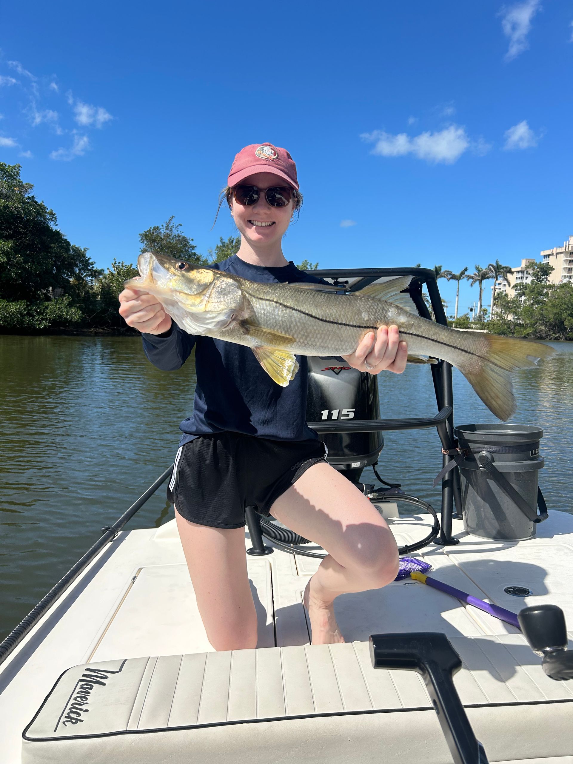 A woman is sitting on a boat holding a large fish.