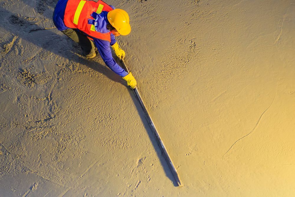 A Construction Worker Wearing a Hard Hat and Safety Vest Is Working on A Concrete Floor — Slippery Solutions In Cranbrook, QLD