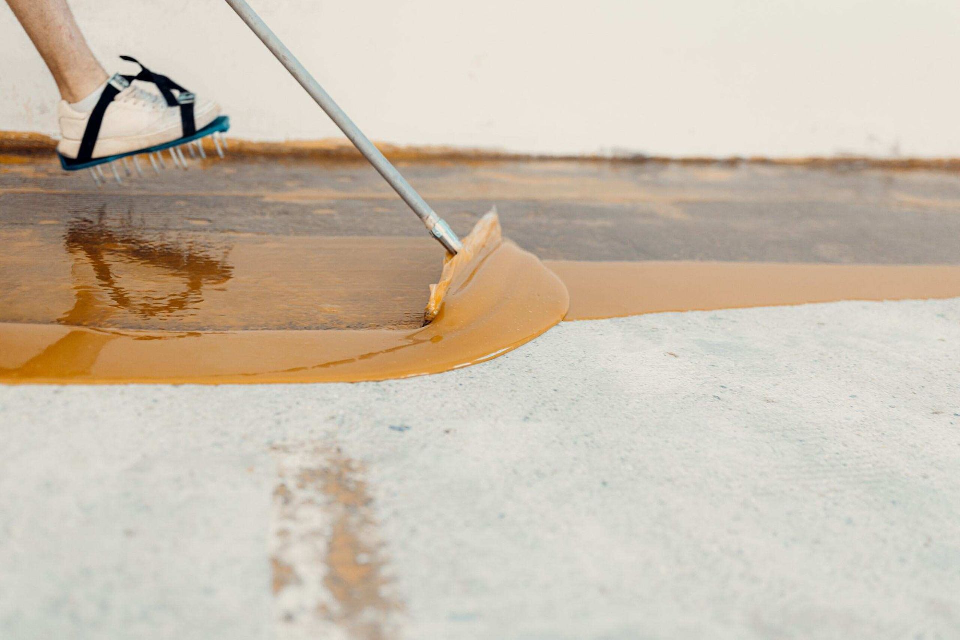 A Person Is Painting a Concrete Floor with A Broom — Slippery Solutions In Cranbrook, QLD 