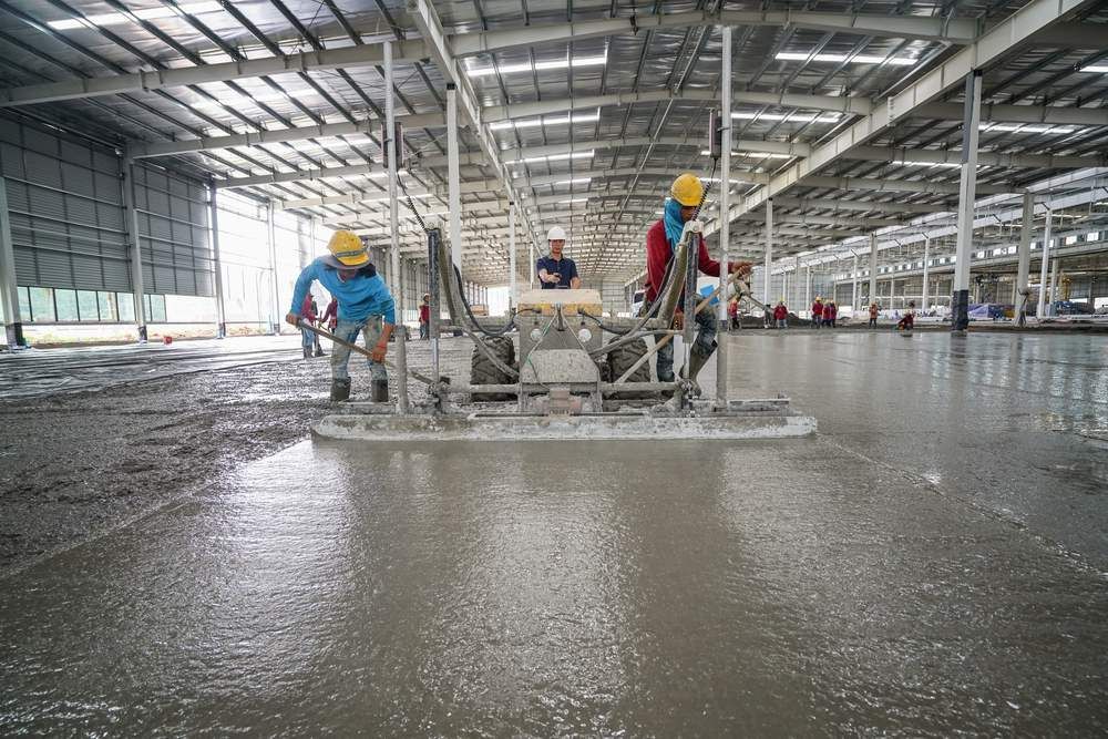 A Group of Construction Workers Are Working on A Concrete Floor in A Large Warehouse — Slippery Solutions In Cranbrook, QLD 