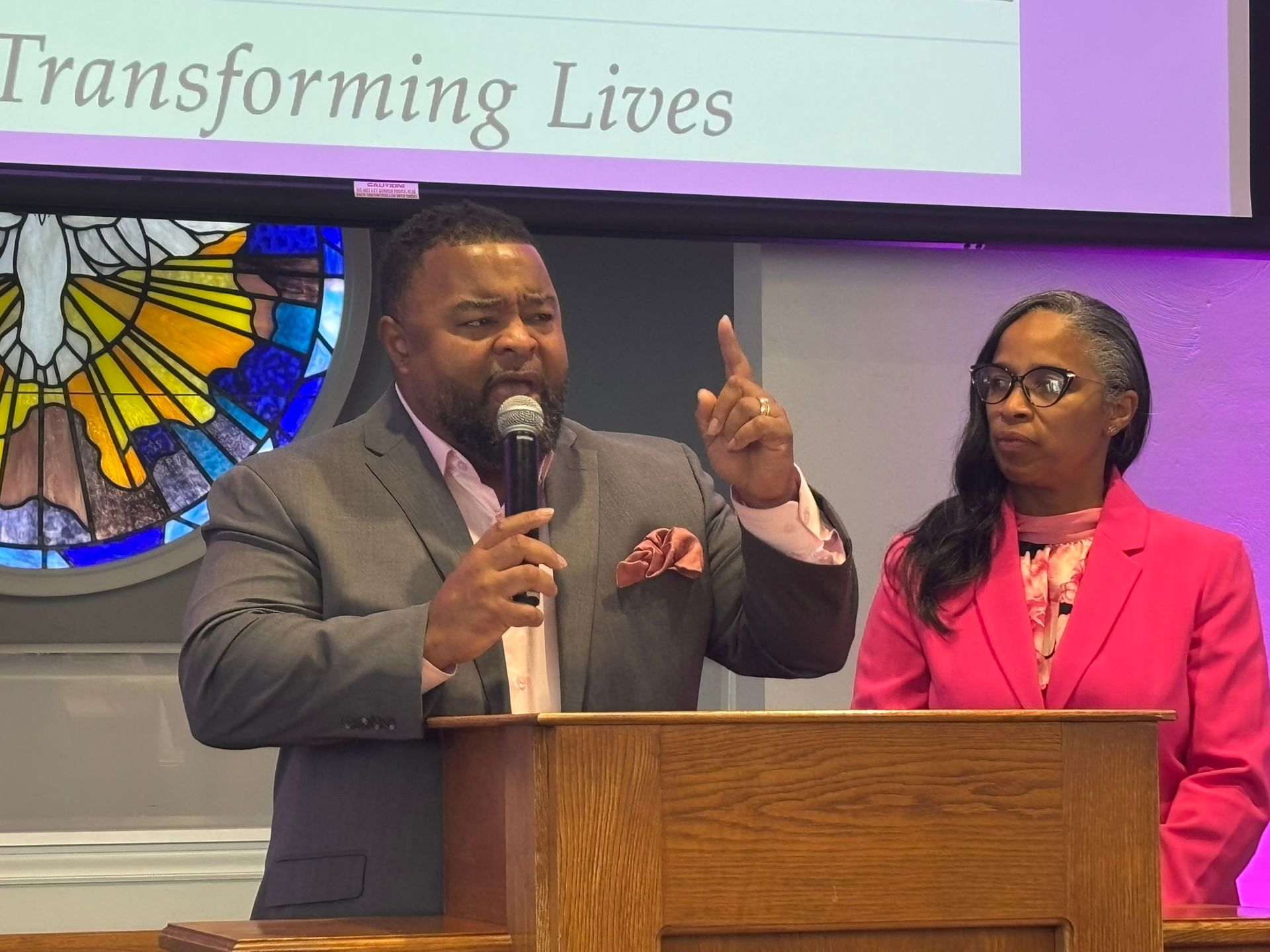 Pastor Jay speaking to congregation with his wife, Rhonda