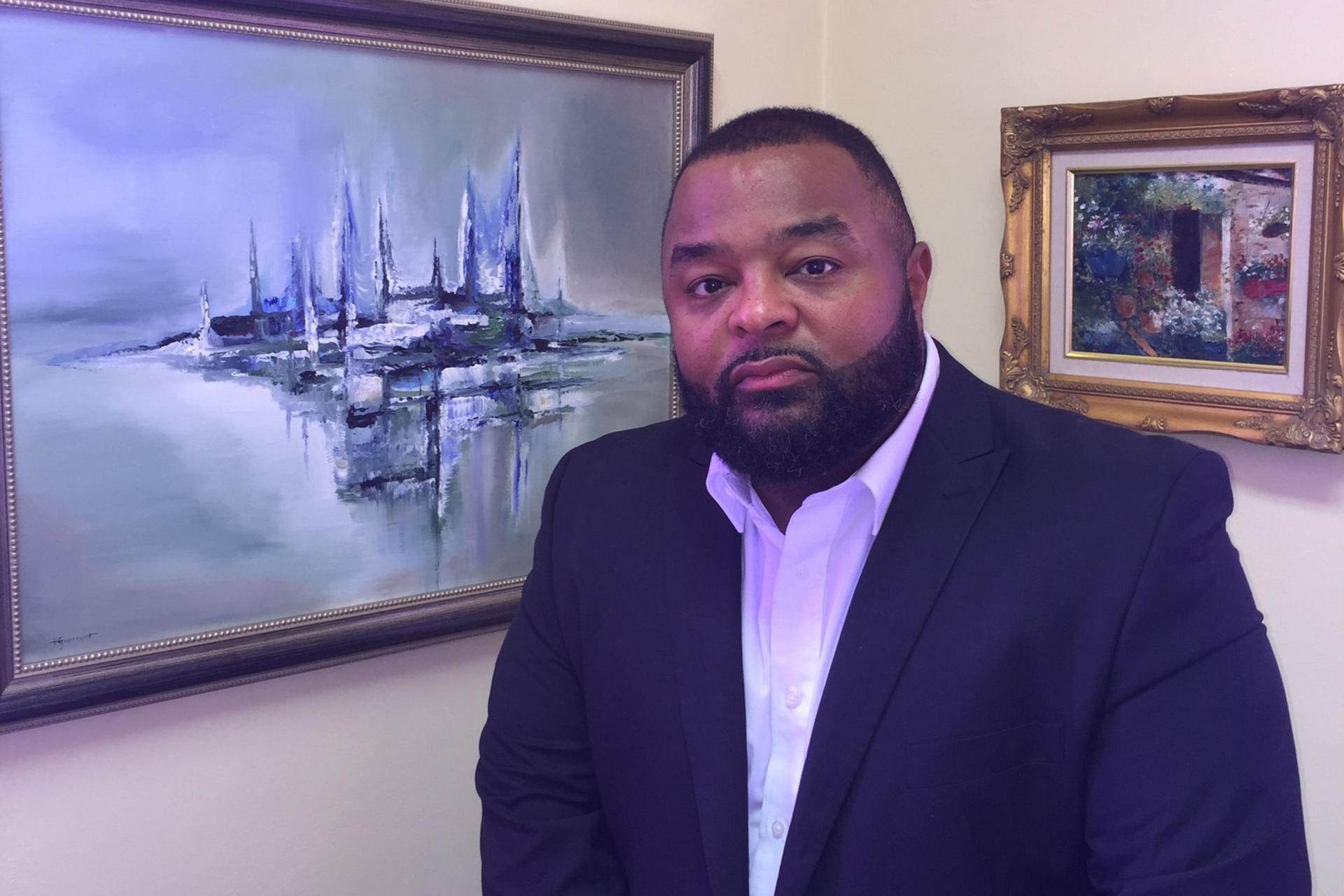 Pastor Jay standing in front of paintings.