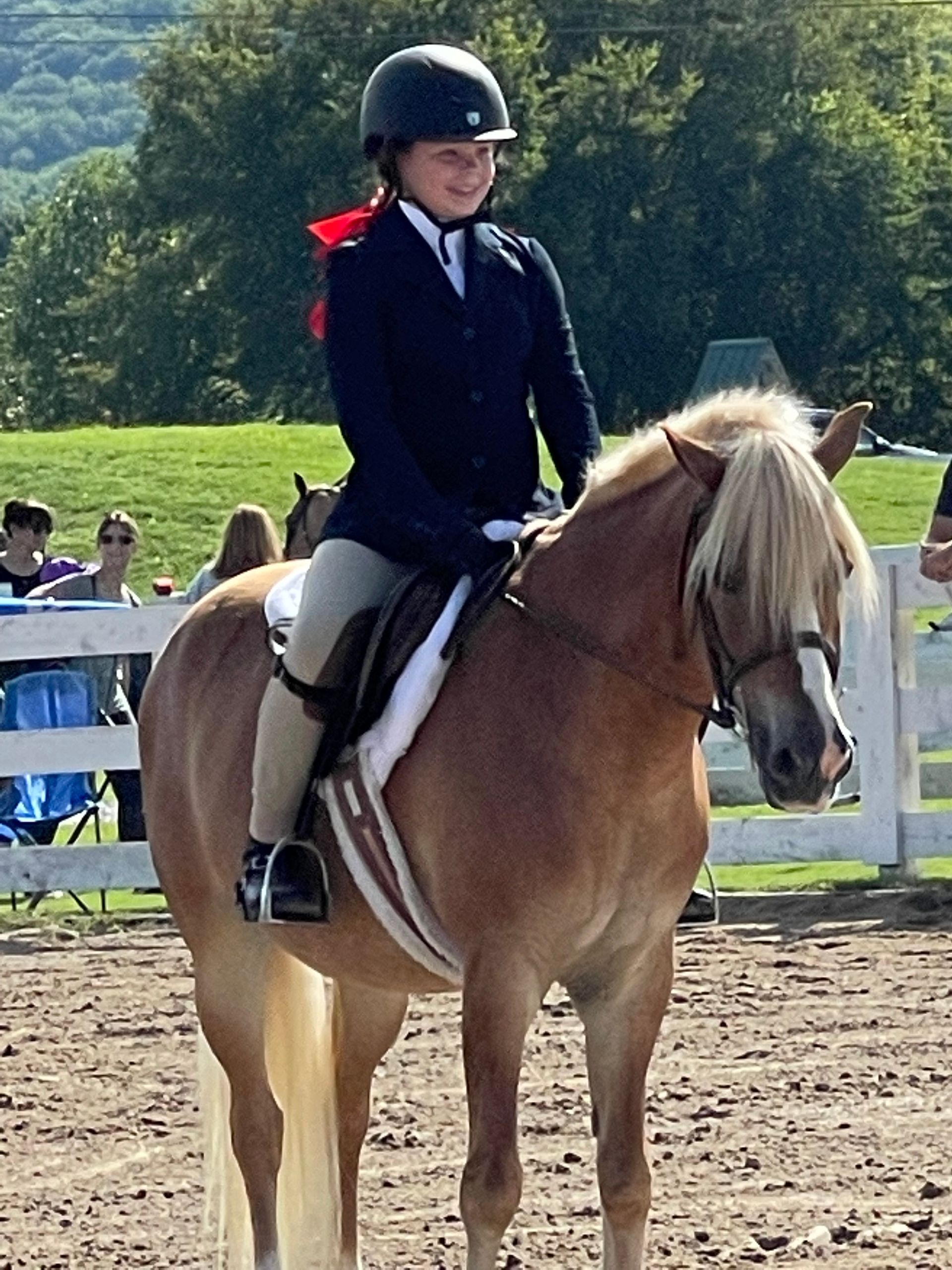 A young girl wearing a helmet is riding a brown horse