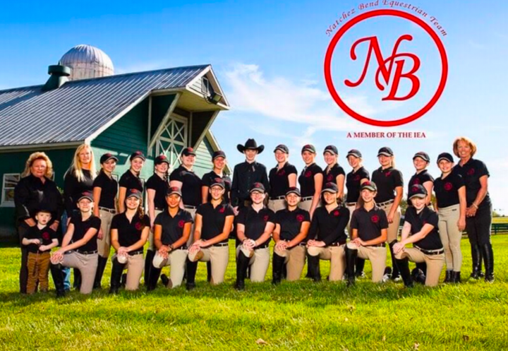 A group of people are posing for a picture in front of a barn.