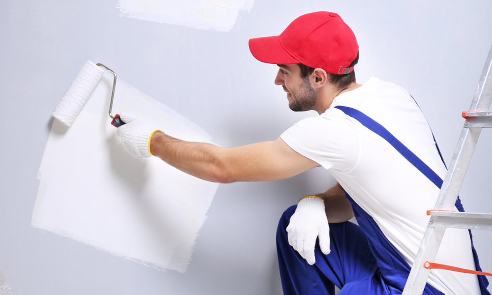 Worker painting a wall during restoration in South Florida.
