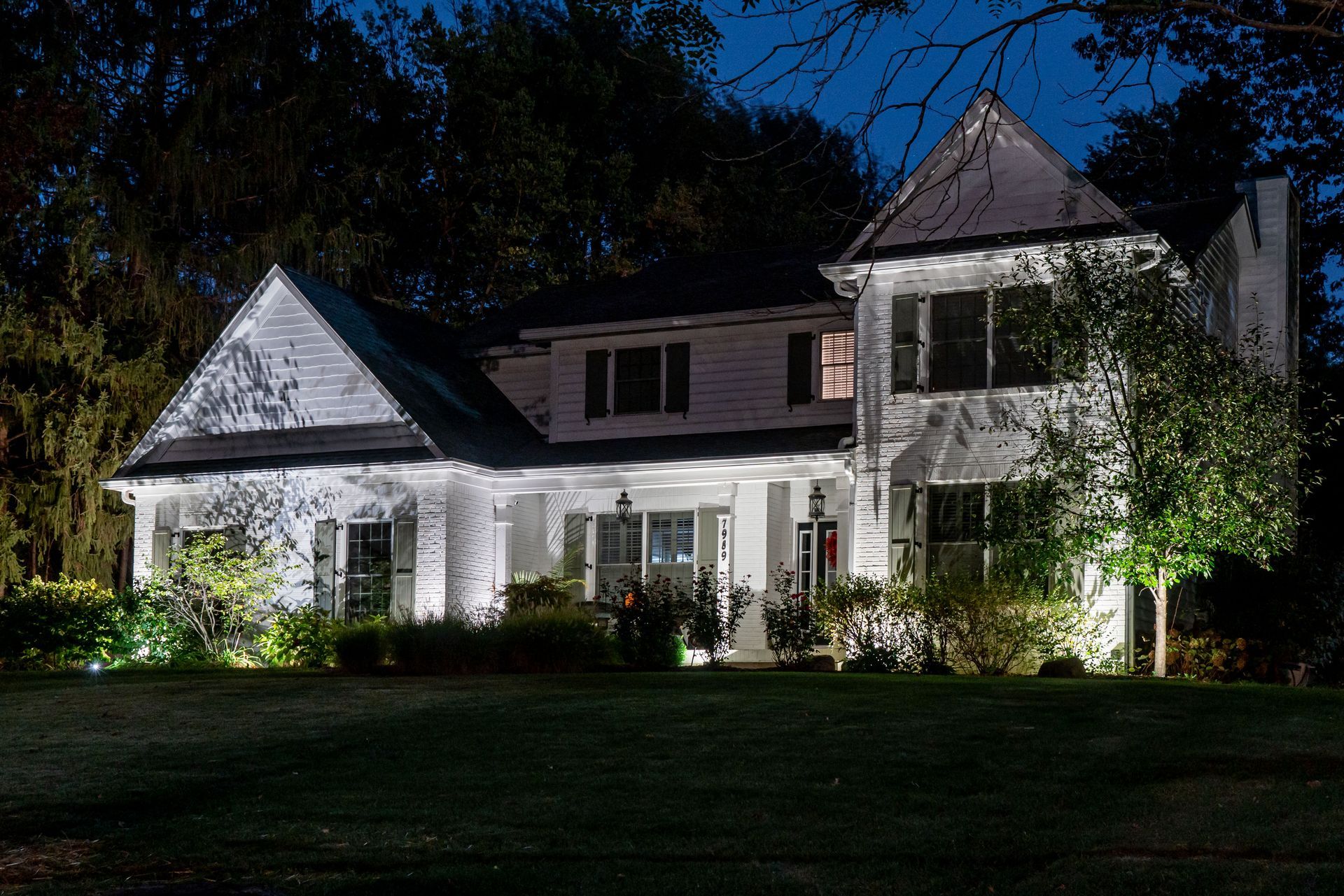 White house illuminated at night with landscape lighting.