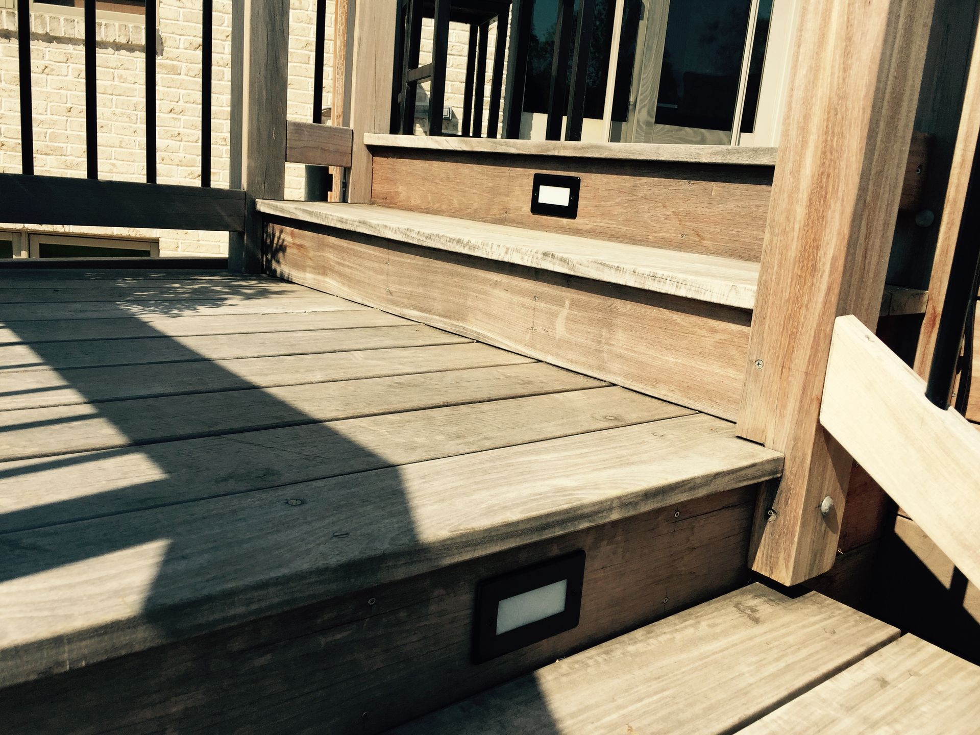 Wooden deck with steps, built-in lights, and railing.