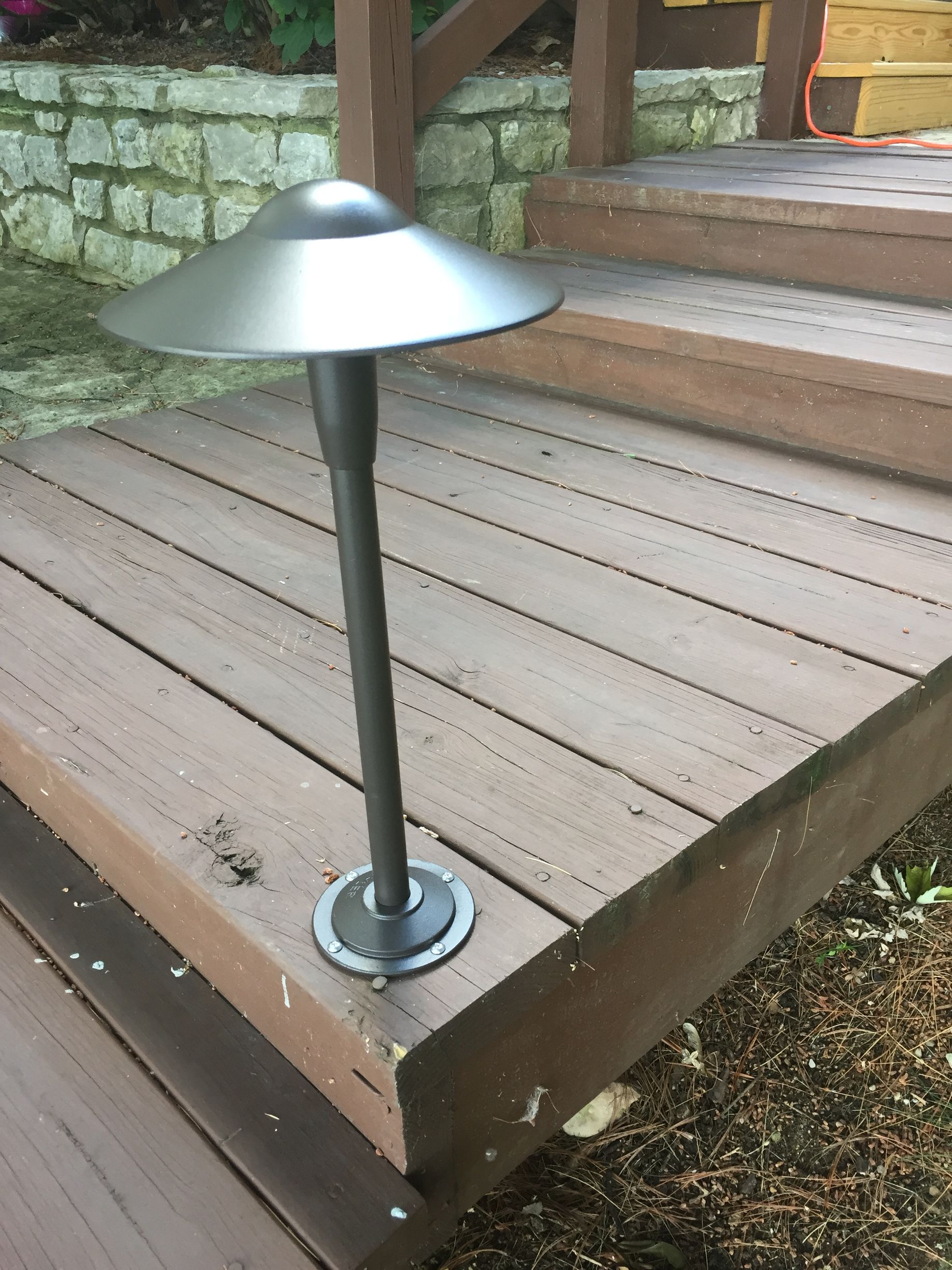A silver outdoor lamp on a wooden deck, illuminating the steps.