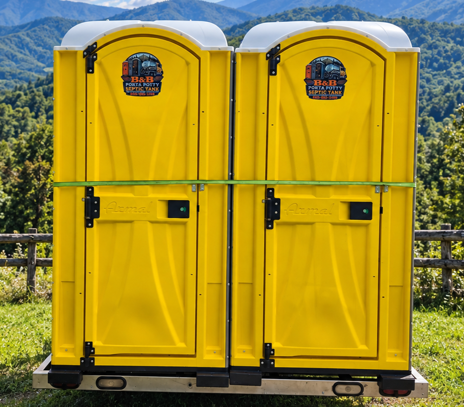Two bright yellow portable toilets on a black platform with a mountain view in the background