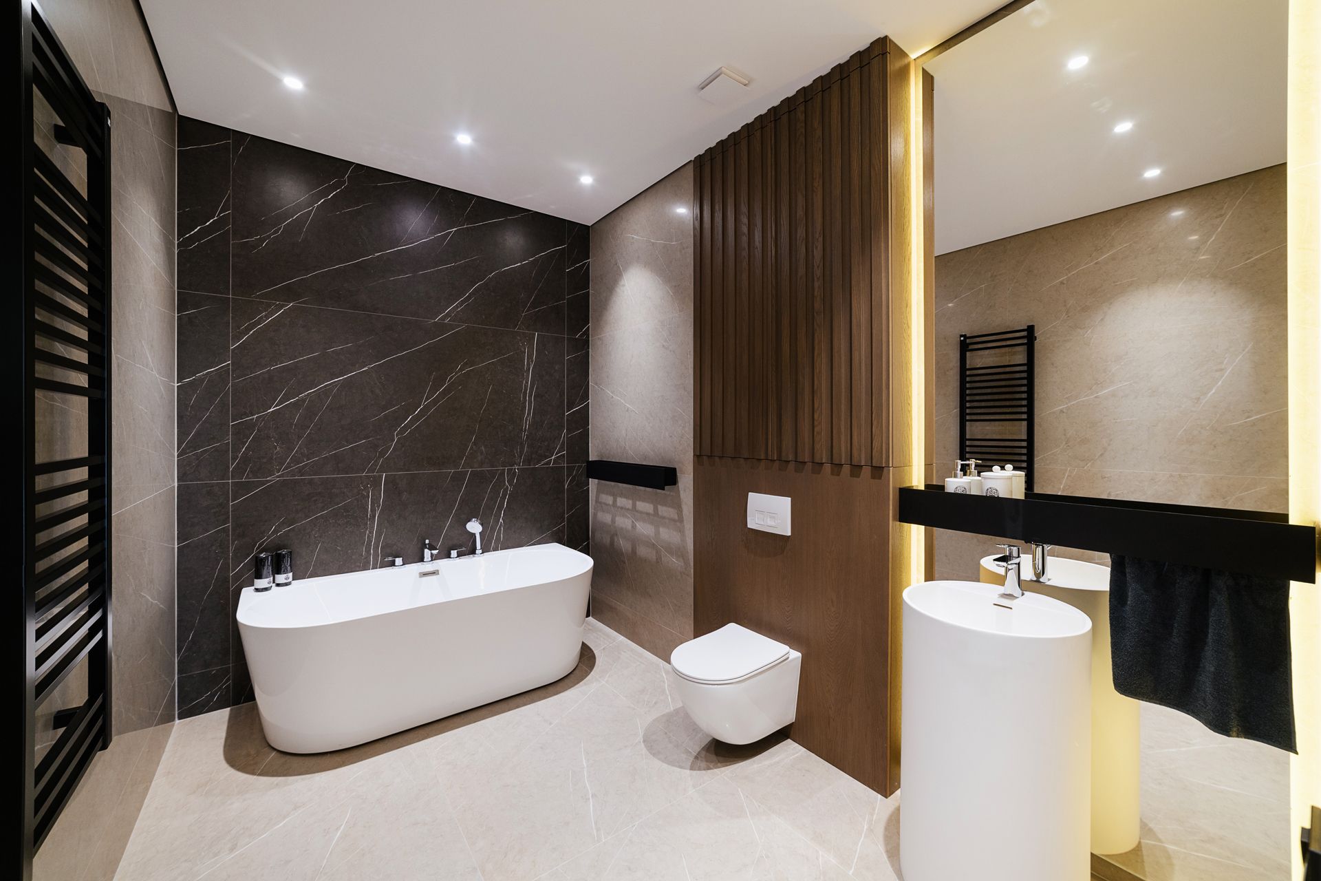 Modern bathroom with a bathtub, toilet, and vanity in a dark, luxurious setting.