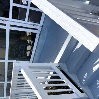 White painted wooden staircase with railing leading up to a platform.